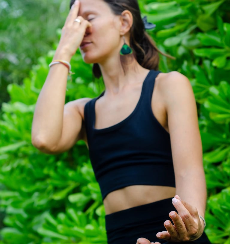 Yoga teacher practicing Nadi Shodhana pranayama seated in nature, everyday essentials