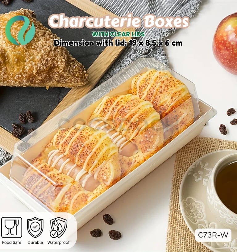 Durable charcuterie box with clear lid containing fresh pastries on a table next to tea and fruit.