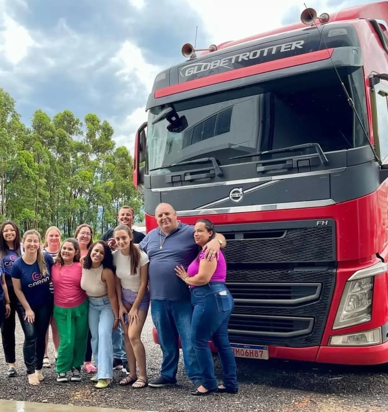 Equipe da Caran Contabilidade junto aos parceiros da Xandão ao lado de caminhão vermelho.