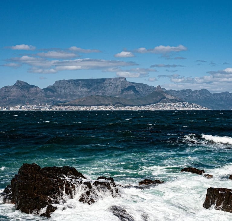 Panoramic view of Table Mountain and Cape Town city skyline across the Atlantic Ocean waves.