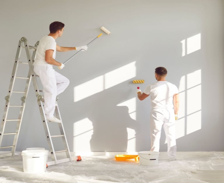 a man and woman painting a wall in a room