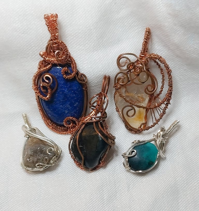 a group of five wire wrapped pendants with a blue and green stone pendant.