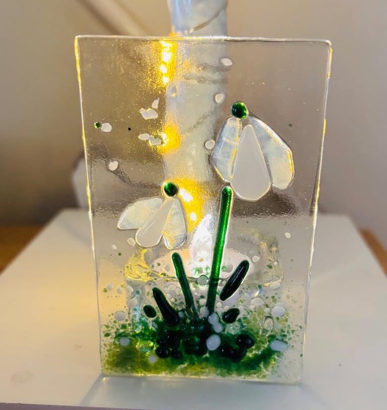 a fused glass tea light holder with a flower inside of it