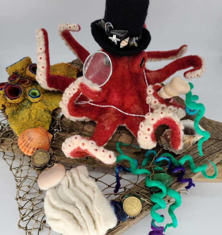 a felted octopus with a hat on a wooden board