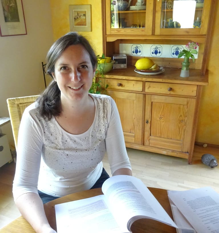a friendly smiling woman sitting at a table with a book