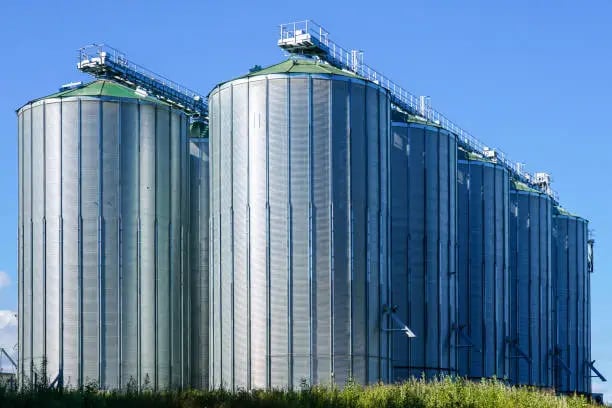 a large group of metal tanks with a blue sky in the background
