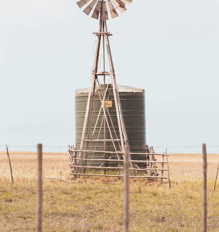 a tank in a field with a windmill