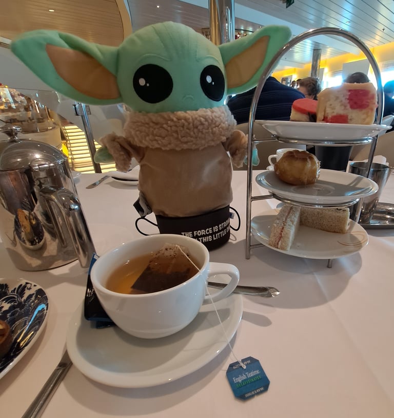 Little Green stuffed Animal on table with Tea cup and cakes