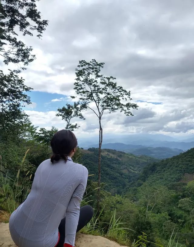 a woman sitting on a rock with a view of the mountains