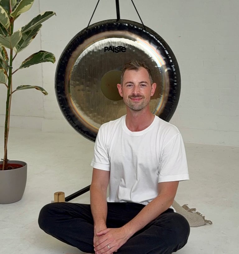 a man sitting in front of a gong in a calming space