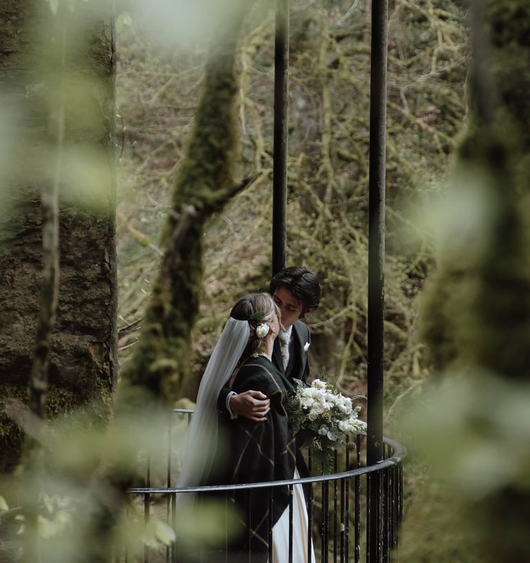 a bride and groom kissing on a bridge