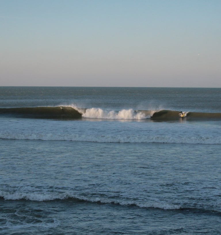 A large A frame peak, with a surfer taking off on the wave peeling to his left.