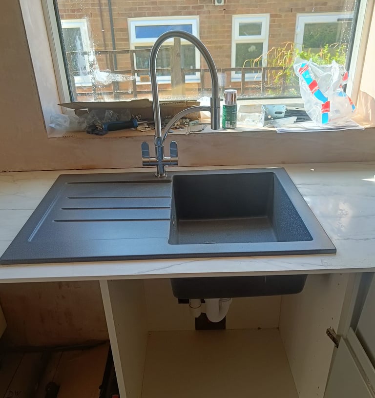 Professional plumber repairing kitchen sink pipework in a residential property