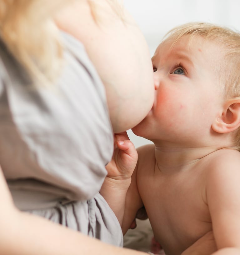 a baby is being fed by a woman in a gray dress