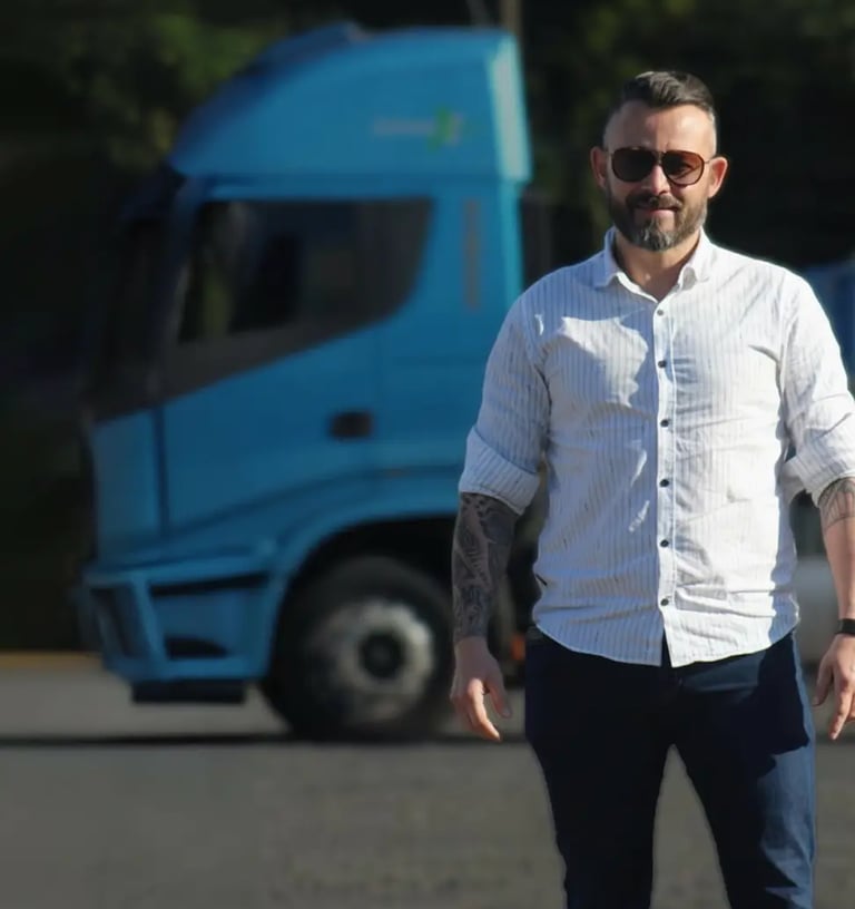 Representante da Extremo Sul Transportes posando ao lado de caminhão azul