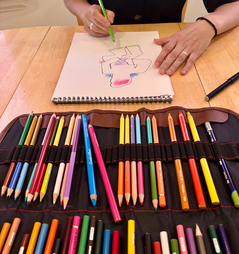 In an expressive arts therapy session, a client is drawing a figure using coloured pencils