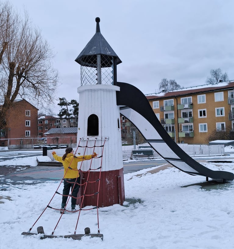 Bild på Jessica framför en fyr på en lekplats. Snö på marken.
