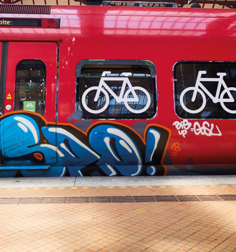 red train with symbols of bicylces at a train station with grafitti on it