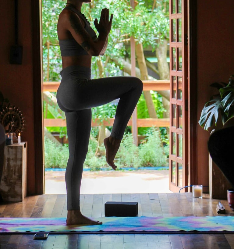 Frau übt Yoga vor einem Fenster mit Blick zum Garten