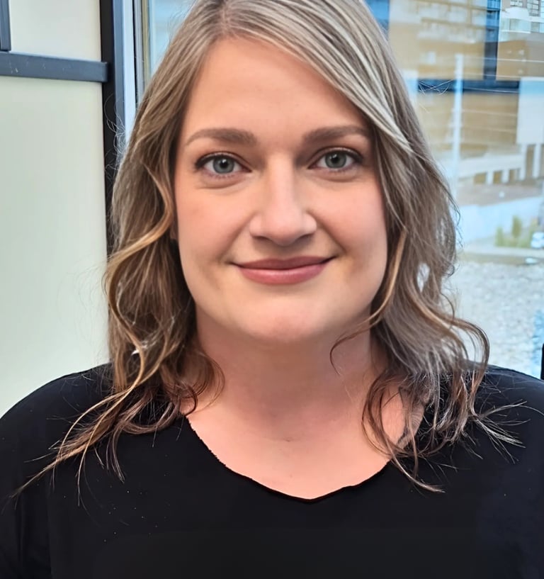 Professional portrait of a smiling woman with wavy blonde hair wearing a black shirt.