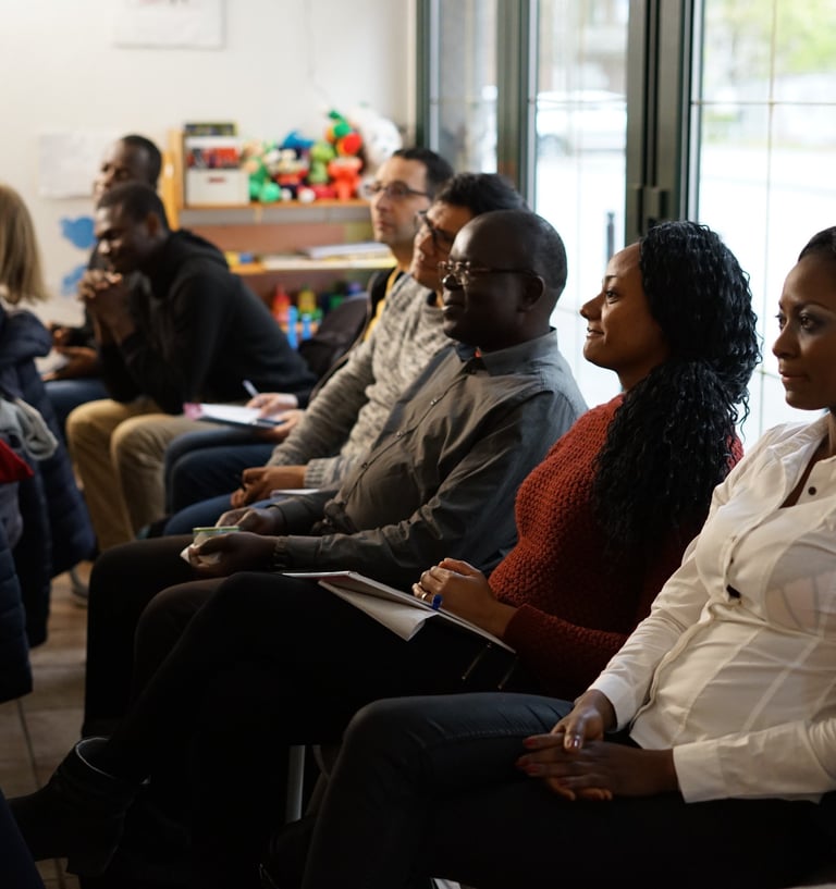 Diverse group of adult students attending a community workshop and taking notes in a classroom.