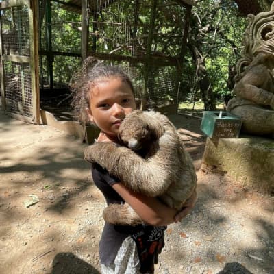 A little girl holding a sloth