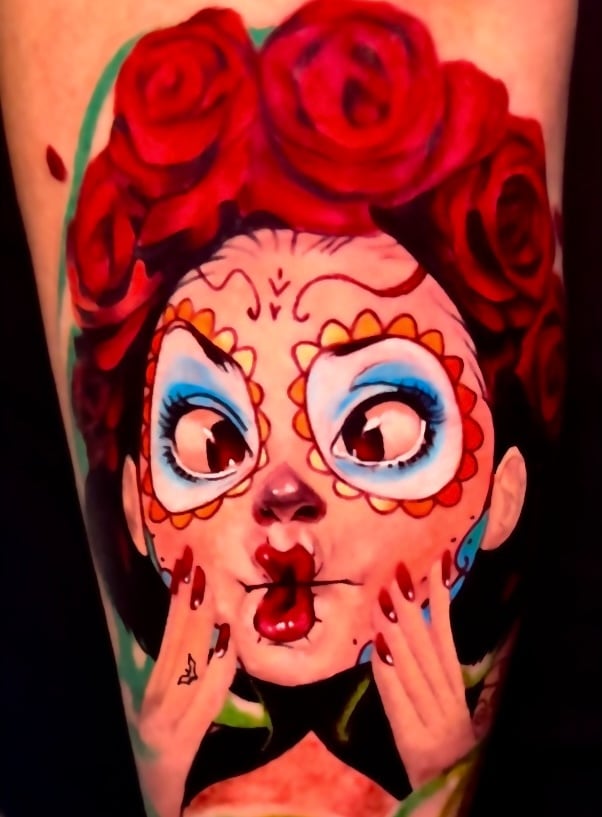 Vibrant Day of the Dead sugar skull girl tattoo with red roses and colorful face paint.