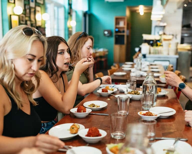 a group of people sitting at a table with plates of food