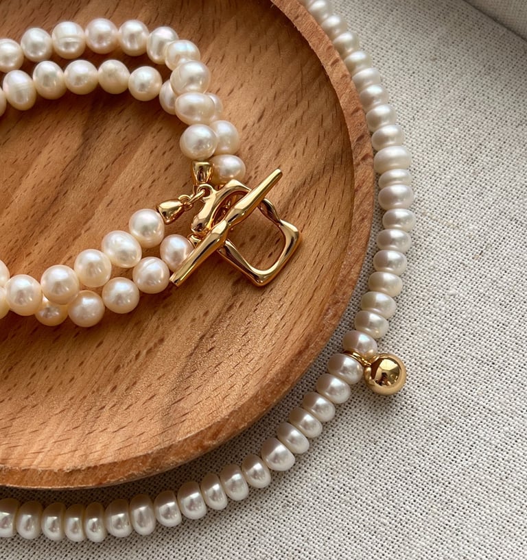 ein Holztablett mit einem Armband und einer Halskette mit goldener Verschluss