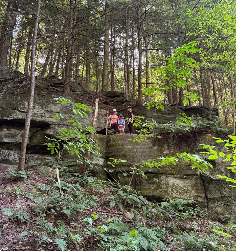 a group of children standing on a rock formation while hiking in Cuyahoga Valley National Park