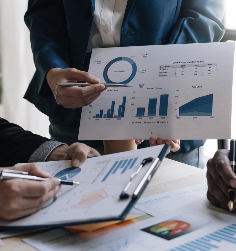 Business team reviewing financial data charts and sales reports in a corporate office meeting.