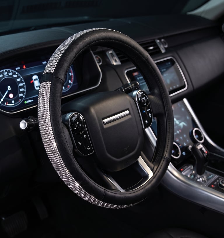 Luxury black leather steering wheel cover with sparkling diamond rhinestones for a car interior.
