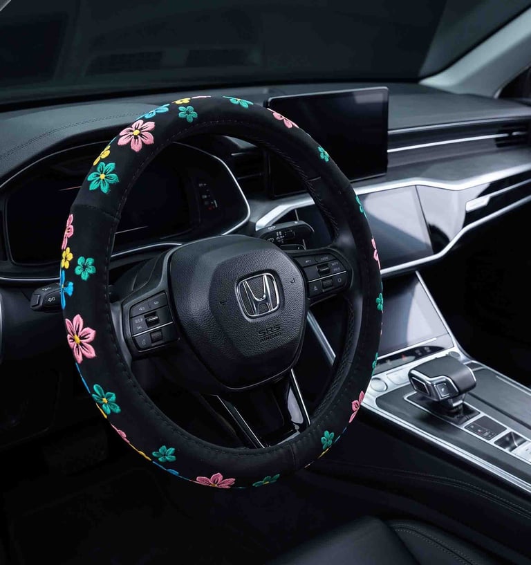 Black suede steering wheel cover with colorful embroidered flowers inside a modern car interior.