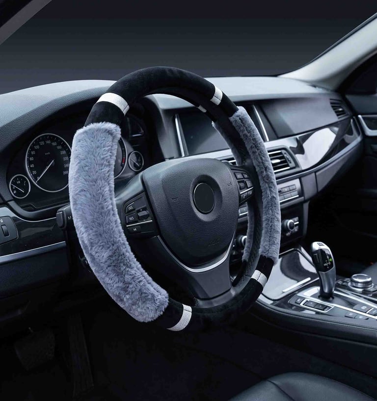 A black and grey faux fur steering wheel cover with sparkling accents inside a luxury car interior.