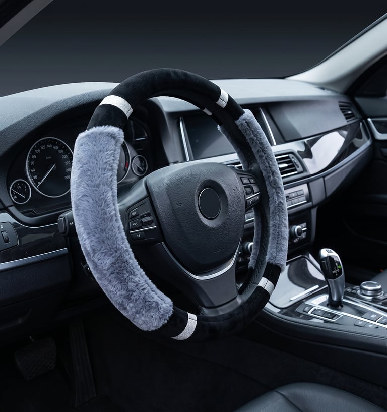 A plush grey and black faux fur steering wheel cover installed on a luxury car dashboard.