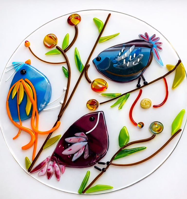 Colorful fused glass birds on branches on circular glass base