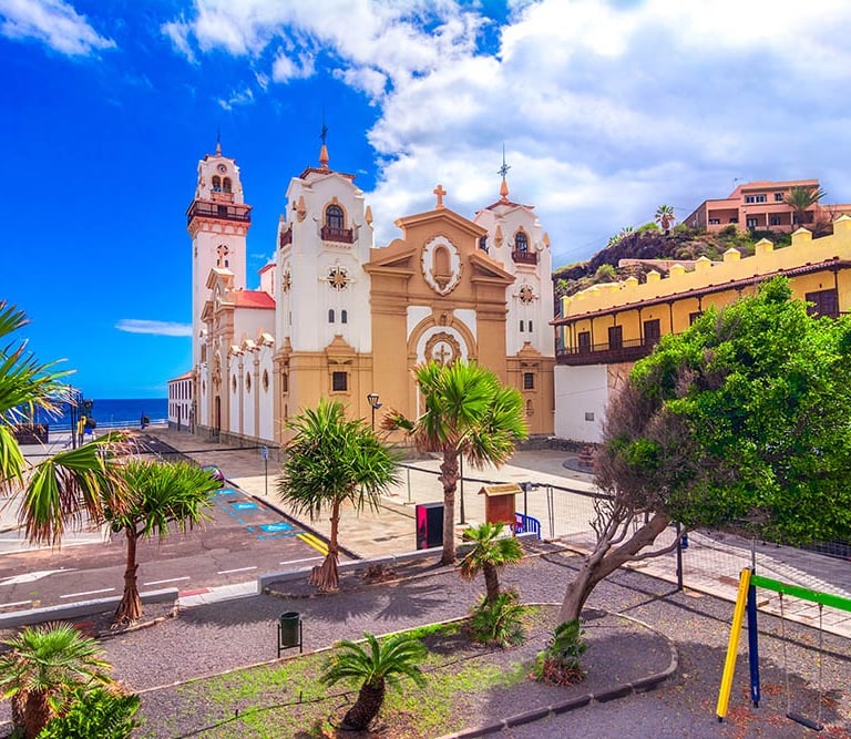 a church with a clock tower and palm trees in Candelaria