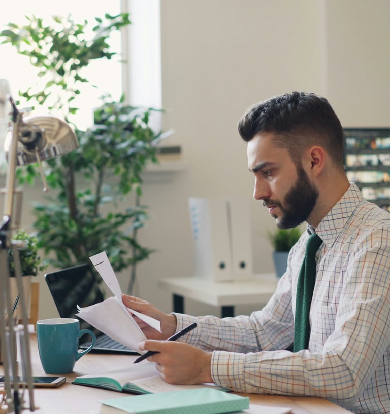 Person using a computer with books, representing cognitive behavioral therapy learning and reflectio