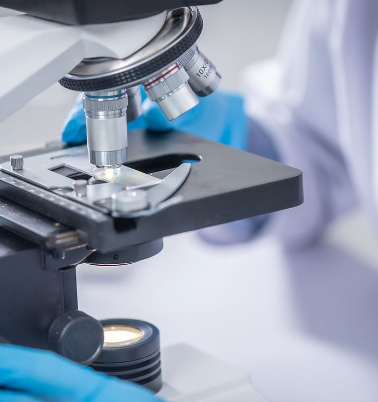 Cientista com luvas azuis ajustando uma lâmina de vidro sob um microscópio de laboratório 