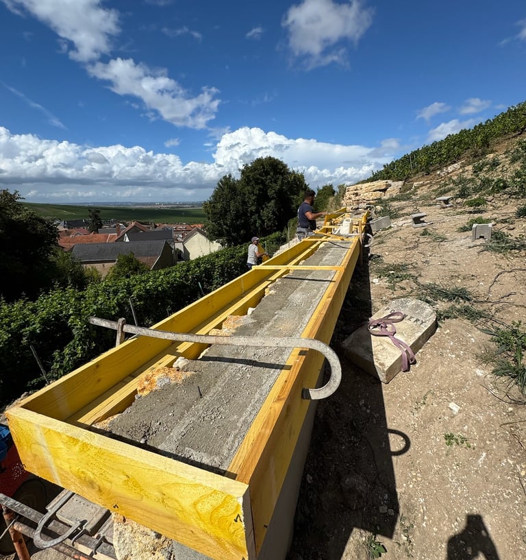 Des ouvriers du bâtiment construisent un mur de soutènement en béton à l'aide d'un coffrage en bois 