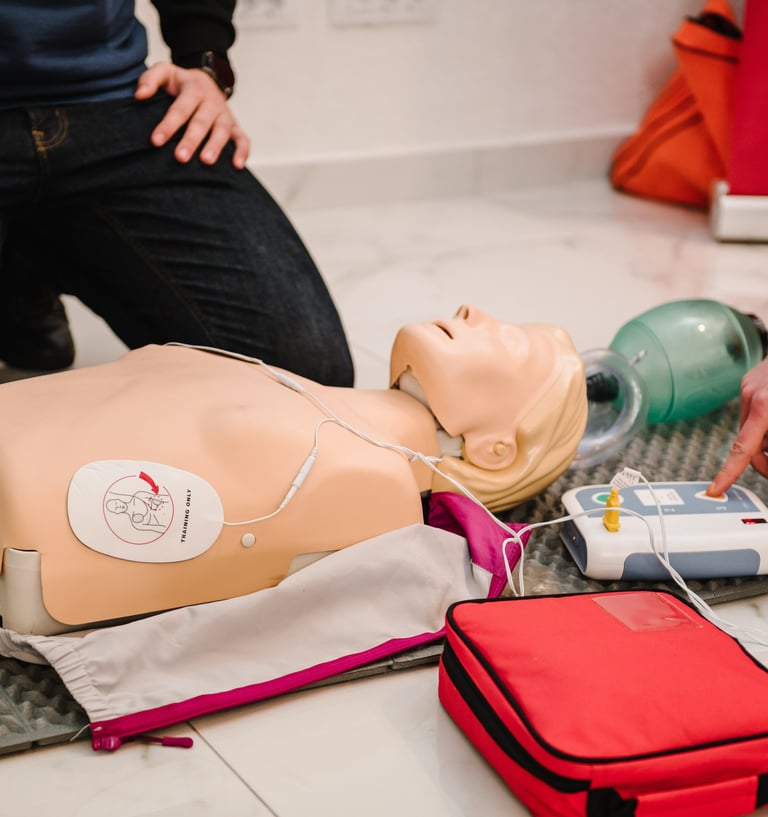 Close up image of CPR mannequin with an AED trainer next to it