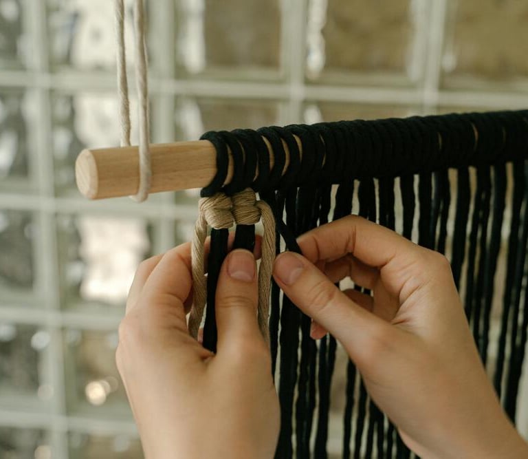 manos creando un adorno tejido de macramé negro y gris