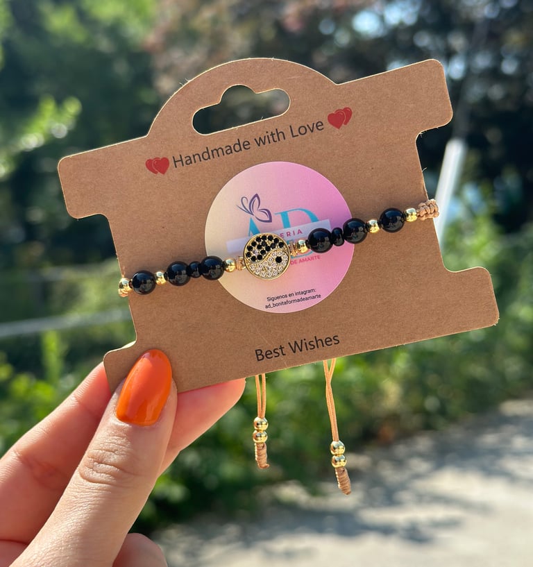 pulsera de perlas negras con cordon cafe y terminado en perlas doradas