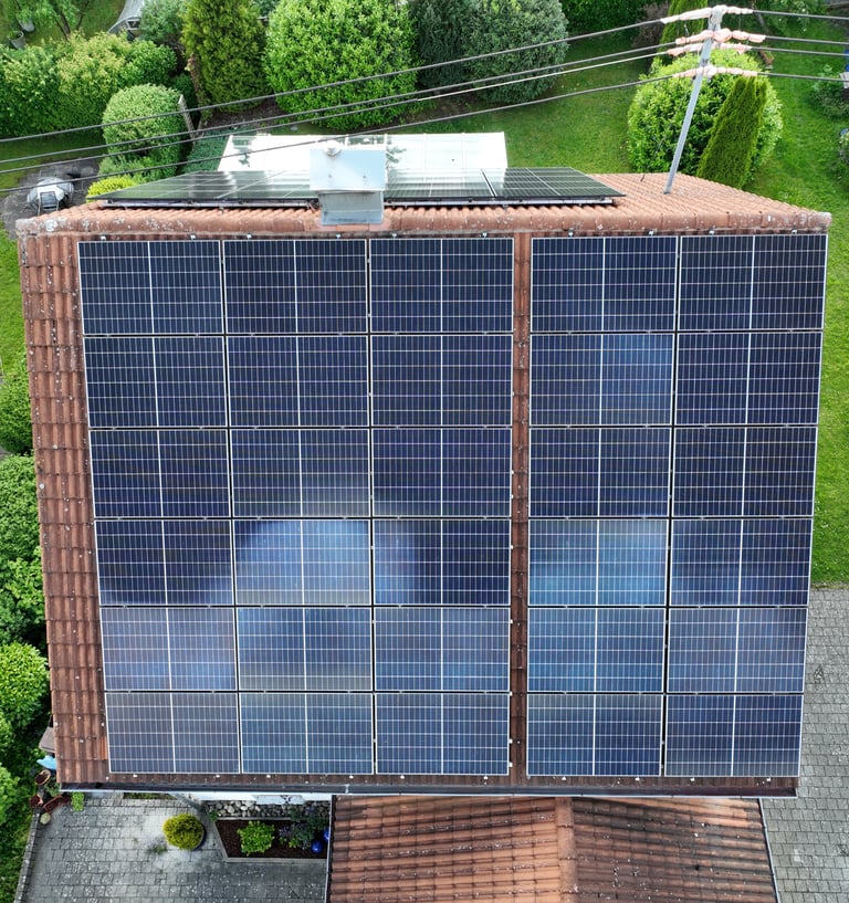 High-angle aerial view of a residential rooftop with a large solar panel array installed for renewable energy.
