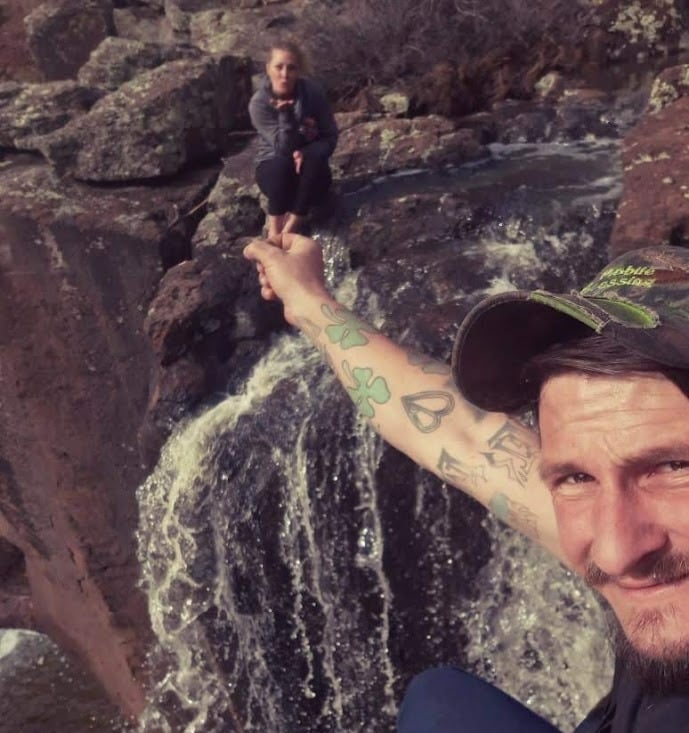 a man with a tattoo on his arm and a woman sitting on a rock