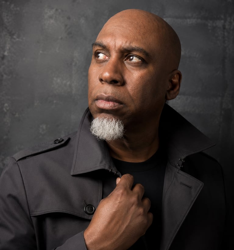 Lee A Jones with a white goatee, wearing a grey trench coat
