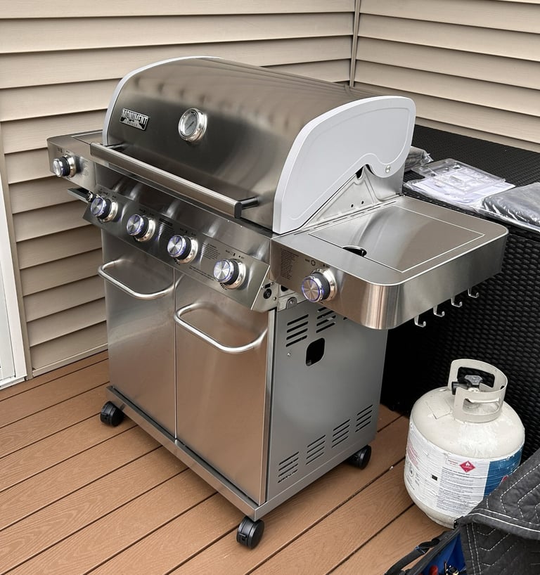 Left side view of stainless steel propane grill showing side burner and hooks