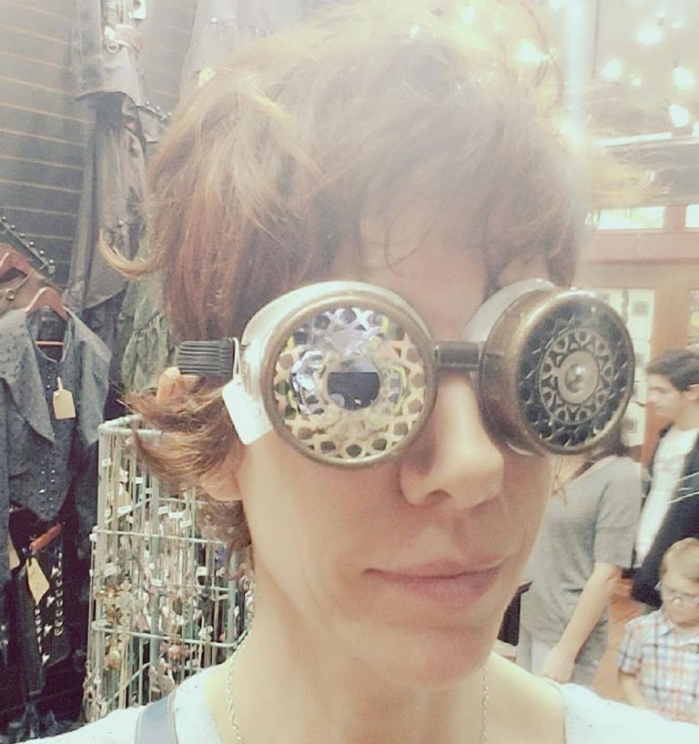 close up head shot of a woman in short hair wearing steampunk goggles