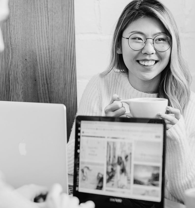 university students sitting at a desk working on their laptops and drinking coffee