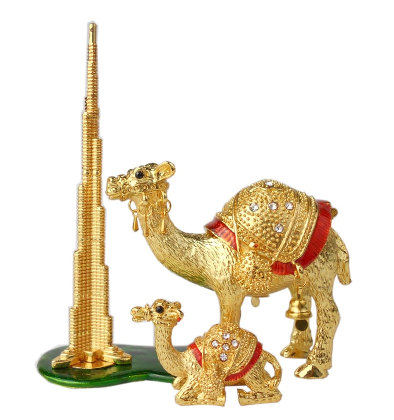 a gold colored camelia figurine of a camel in front of a tall